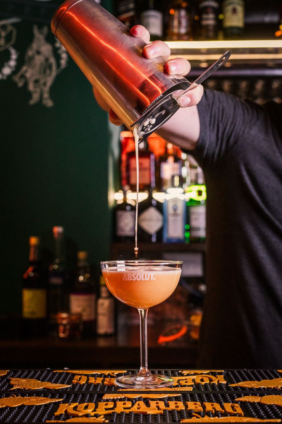 Cocktail being made from stocked bar shelves